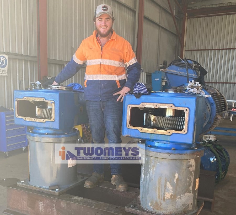 Twomeys tradesperson beside two gearbox drive assemblies with inspection covers removed for overhaul