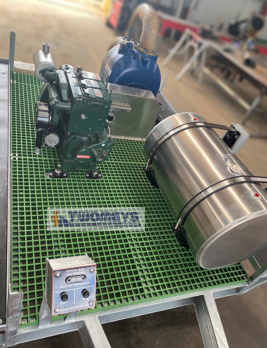 Deck of the pump trailer showing the diesel engine, pump, stainless fuel tank and stainless control box on green grating